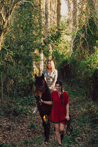 Woman with dog against plants and trees in park