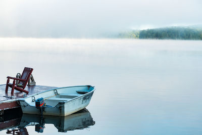 Boat moored in lake against sky
