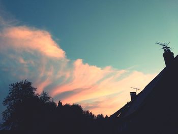 Low angle view of silhouette trees and building against sky