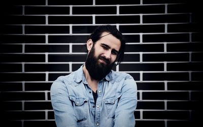 Portrait of young bearded man against brick wall