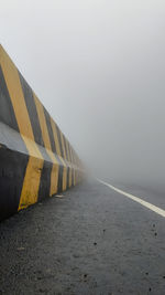 Empty road by wall against sky