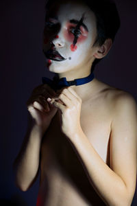 Portrait of young man making face against black background