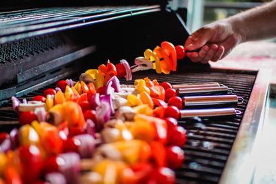 Cropped hand of man roasting vegetable on barbecue grill