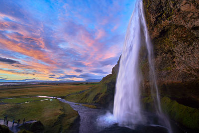 View of waterfall against cloudy sky