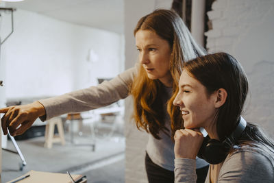 Mature hacker talking with female colleague while working in office