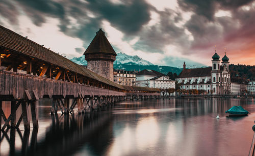 Bridge over river by buildings against sky