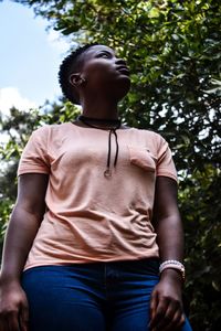 Low section of young man looking away while sitting on tree