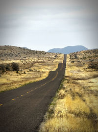 Road amidst field against sky