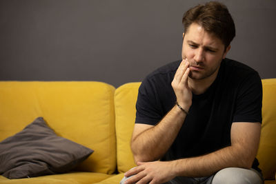 Young man sitting on sofa at home