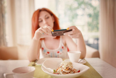 Young woman using laptop while sitting on table