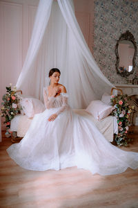 Woman sitting on white wall