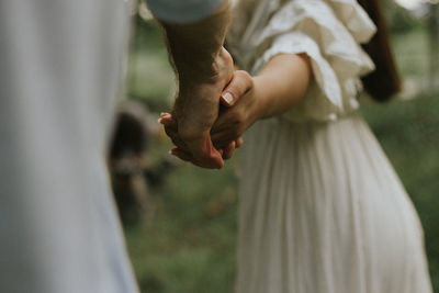 Midsection of couple holding hands