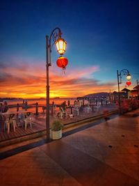 Street lights on footpath in city at sunset