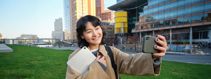 Young woman using mobile phone while standing in city