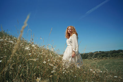 Woman standing on field against blue sky