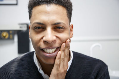 Portrait of young man with toothache sitting in hospital