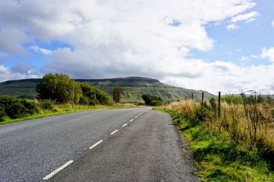Road amidst field against sky