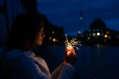 Close-up of woman holding illuminated lighting equipment at night