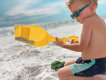 Rear view of a boy with arms raised at beach