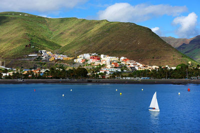 Sailboat in sea by mountains against sky