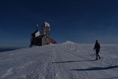 Man on snow covered land against sky