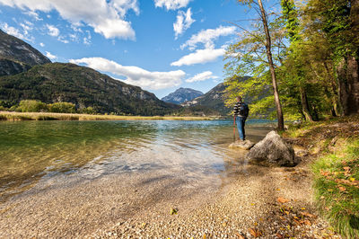 Rear view of man by lake against sky