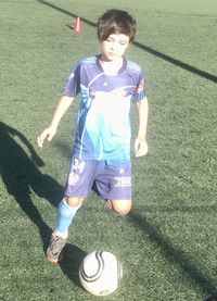 Portrait of boy playing with ball on grass