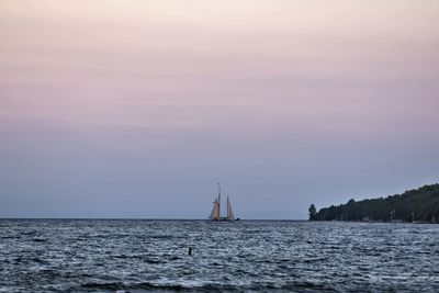 Sailboat sailing on sea against sky during sunset