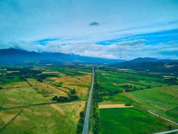 Aerial view from drone flight over different agricultural fields and the road to the mountains