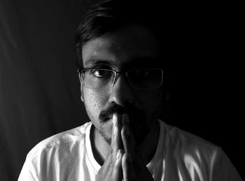 Close-up portrait of young man smoking cigarette against black background