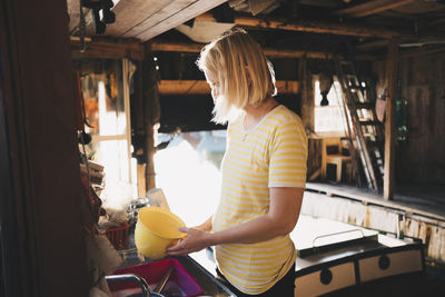 Woman washing container in kitchen at holiday villa