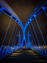 Illuminated bridge against blue sky at night