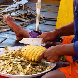 Cropped image of man cutting pineapple on floorboard