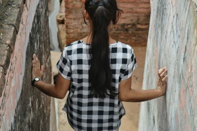 Rear view of teenage girl standing amidst walls