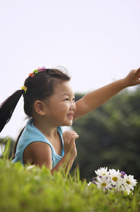 Girl with bunch of flowers lying on grassy field at park