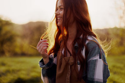 Smiling woman standing on field during sunset