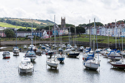 Boats moored in lake against cloudy sky