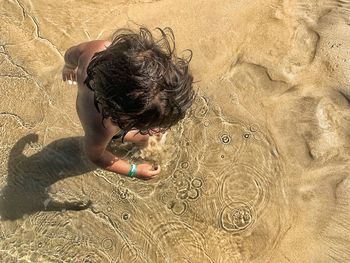 High angle view of shirtless boy on sand at beach