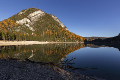 Scenic view of lake by mountains against clear blue sky