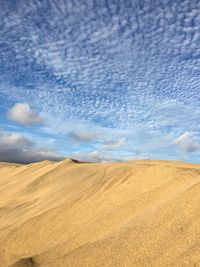 Scenic view of sand dunes against sky