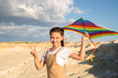 Rear view of woman holding umbrella at beach against sky