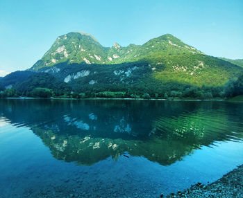 Scenic view of lake by mountains against clear sky