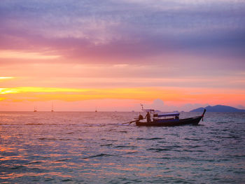 Fishing boat in sea against sky during sunset