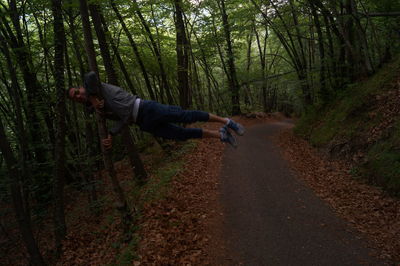 Full length of woman standing on tree trunk in forest