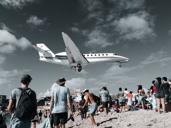 People at airplane against sky
