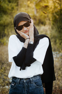 Young woman touching face while standing outdoors