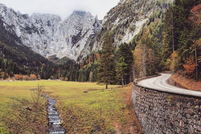 Road amidst trees and mountains against sky