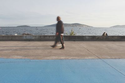 Side view of woman running on shore against sea