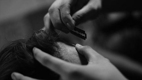 Close-up of person cutting hair with razor blade