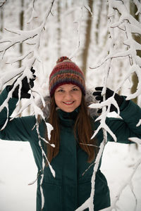 Portrait of smiling young woman standing against curtain